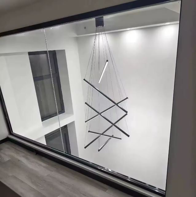 Suspension LED noire à tiges croisées, parfaite pour un intérieur minimaliste avec grande hauteur sous plafond ou mezzanine.