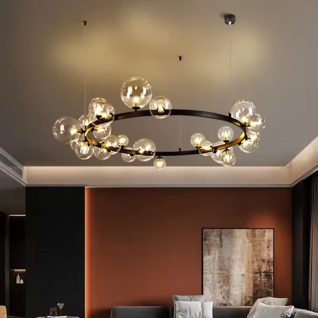 Suspension bulle en verre transparent avec structure noire, créant une ambiance chic et chaleureuse dans un salon moderne.