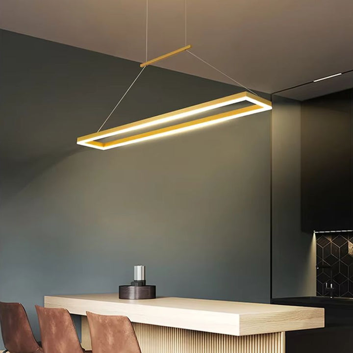 Suspension cadre LED doré au design italien épuré, installée au-dessus d’un bar de cuisine aux lignes modernes