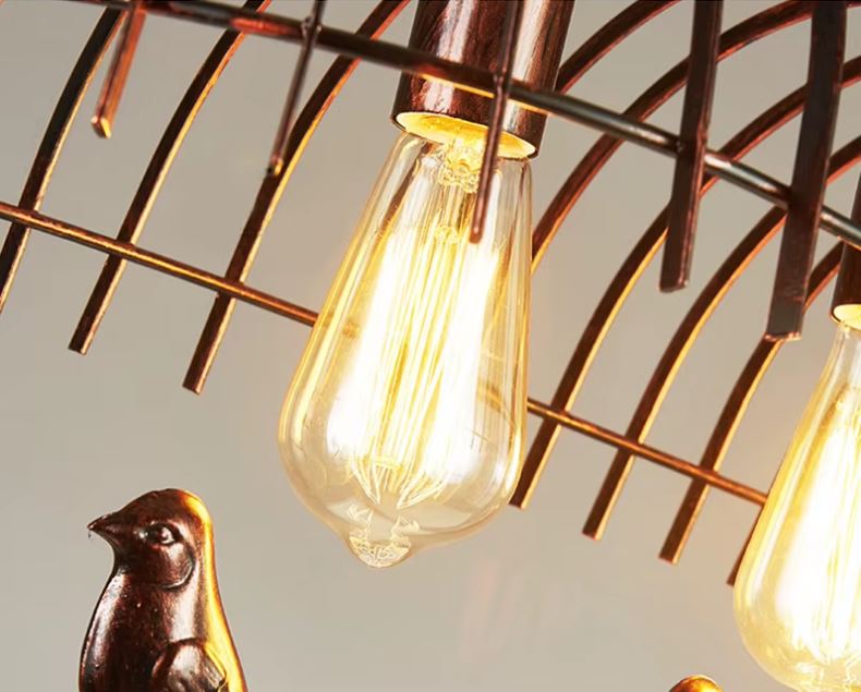 Gros plan sur l'ampoule Edison d'une suspension cage oiseau, un luminaire vintage avec une lumière chaleureuse et décorative.