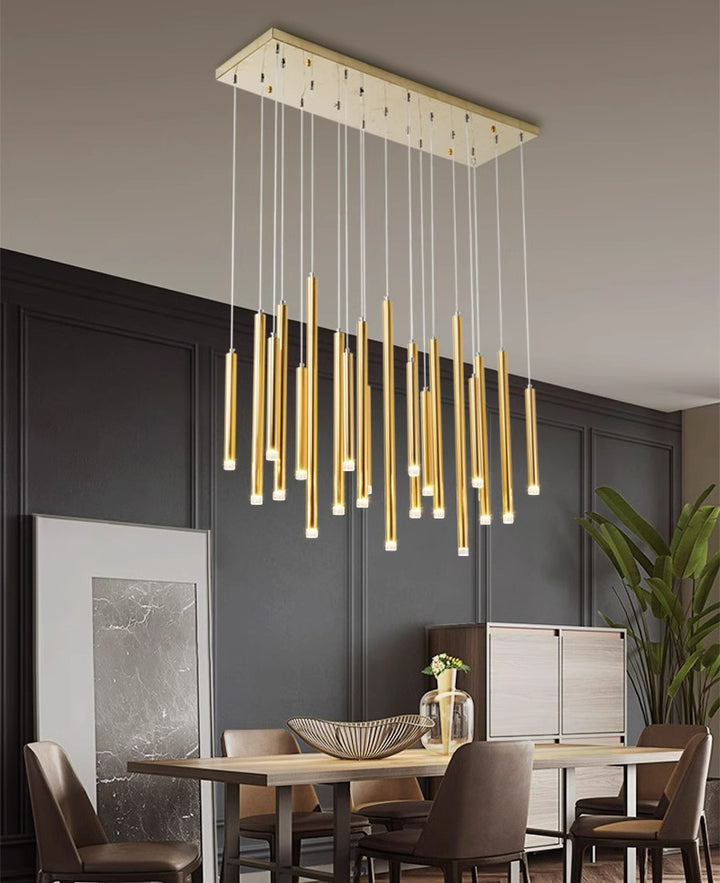Suspension cascade architecturale à tubes lumineux dorés installée au-dessus d'une table de salle à manger.