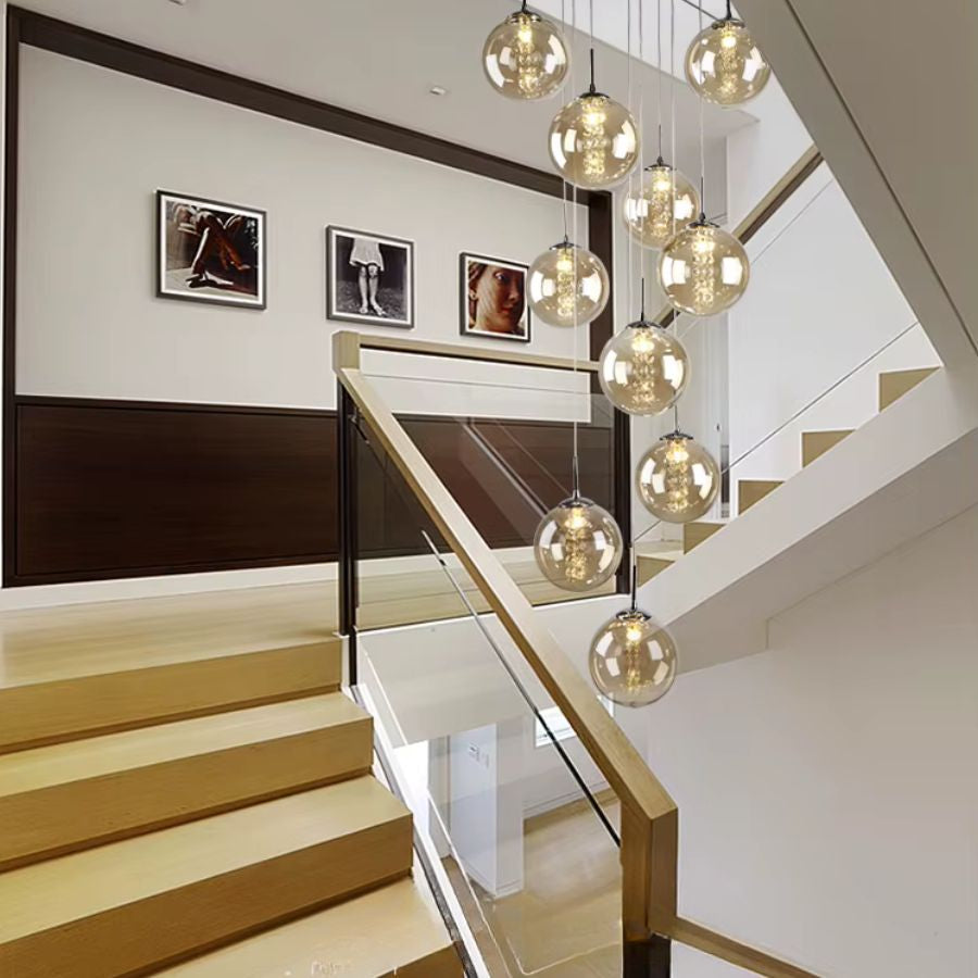 Suspension cascade de boules en verre cognac dans une cage d’escalier, luminaire sculptural au style contemporain