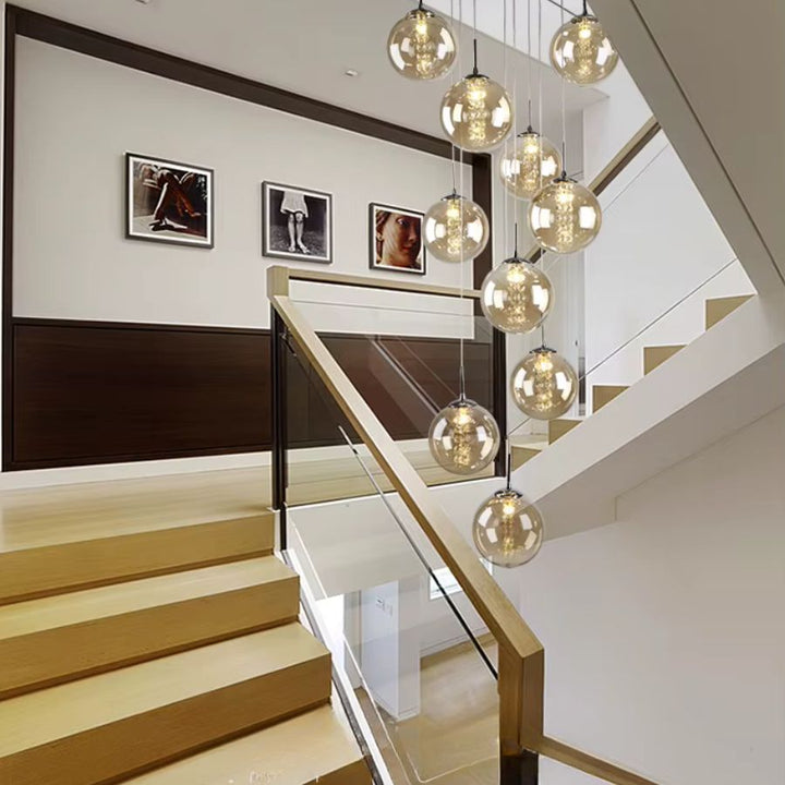 Suspension cascade de boules en verre cognac dans une cage d’escalier, luminaire sculptural au style contemporain