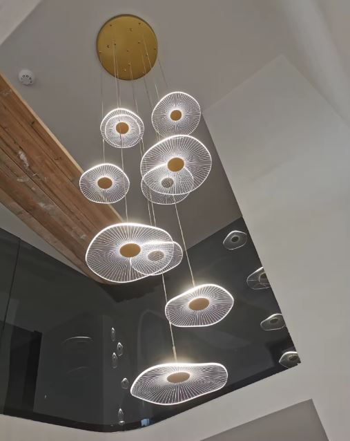 Suspension cascade à disques lumineux dorés, style contemporain, aérien et raffiné pour cage d’escalier.