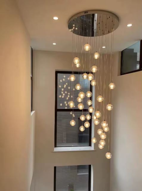 Suspension en cascade fluide de globes en verre pour plafond haut, éclairage design élégant et composition aérienne.