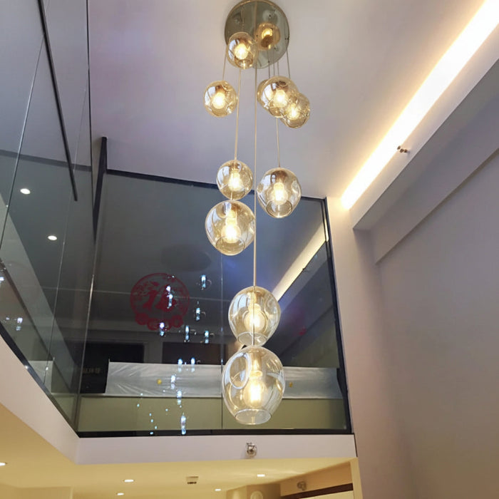 Suspension Cascade de Globes en Verre installée en hauteur près d’un escalier pour sublimer un espace intérieur contemporain