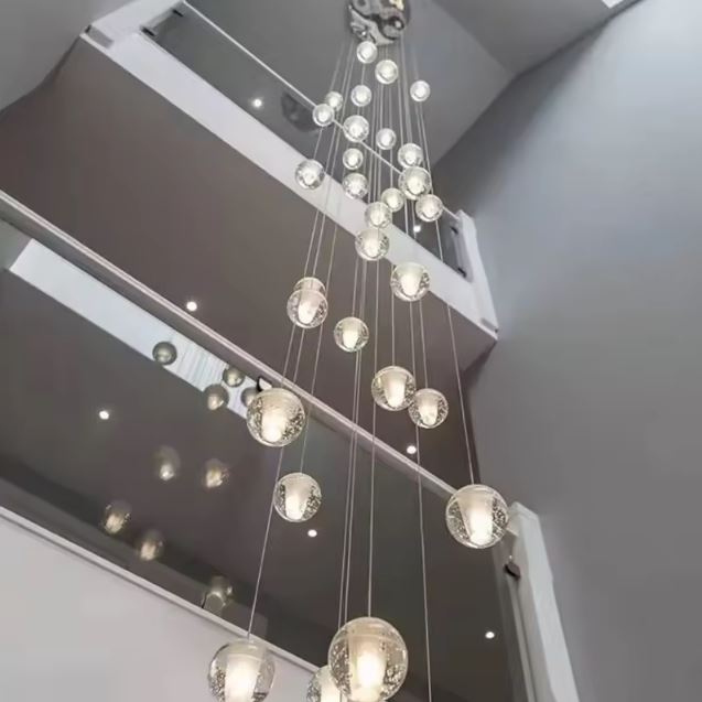 Suspension monumentale en cascade de globes en verre pour escalier contemporain et grand volume architectural.