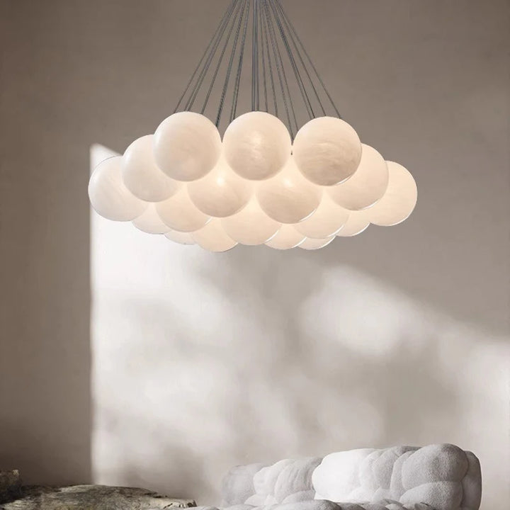 Suspension en cascade de globes en verre opalin blanc diffusant une lumière douce dans un intérieur au style japandi