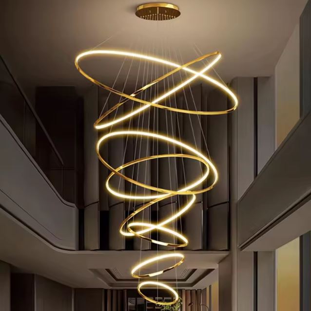 Suspension cascade grande hauteur à anneaux LED infinis dorés, ambiance contemporaine luxueuse pour hall d'accueil.