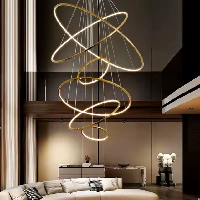Suspension cascade grande hauteur LED dorée au style sculptural, idéale pour un salon design avec plafond cathédrale chaleureux.