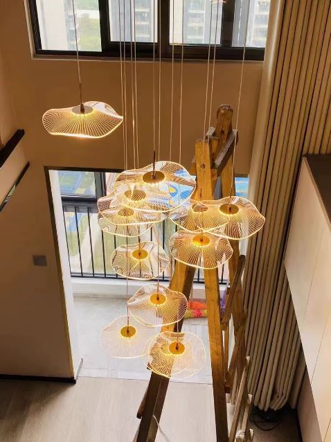Vue réelle d’une suspension cascade installée dans un intérieur moderne avec grande hauteur et escalier en bois.