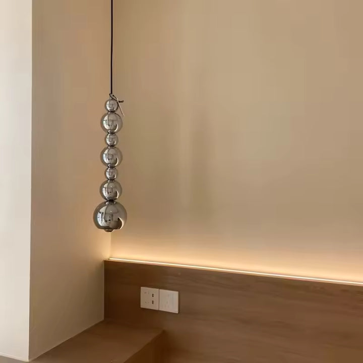 Près du chevet, cette suspension en cascade de sphères chromées apporte une touche sculpturale et contemporaine