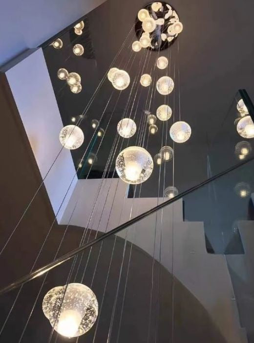 Suspension cascade de sphères en verre transparent pour escalier à plafond haut, design contemporain et élégant.