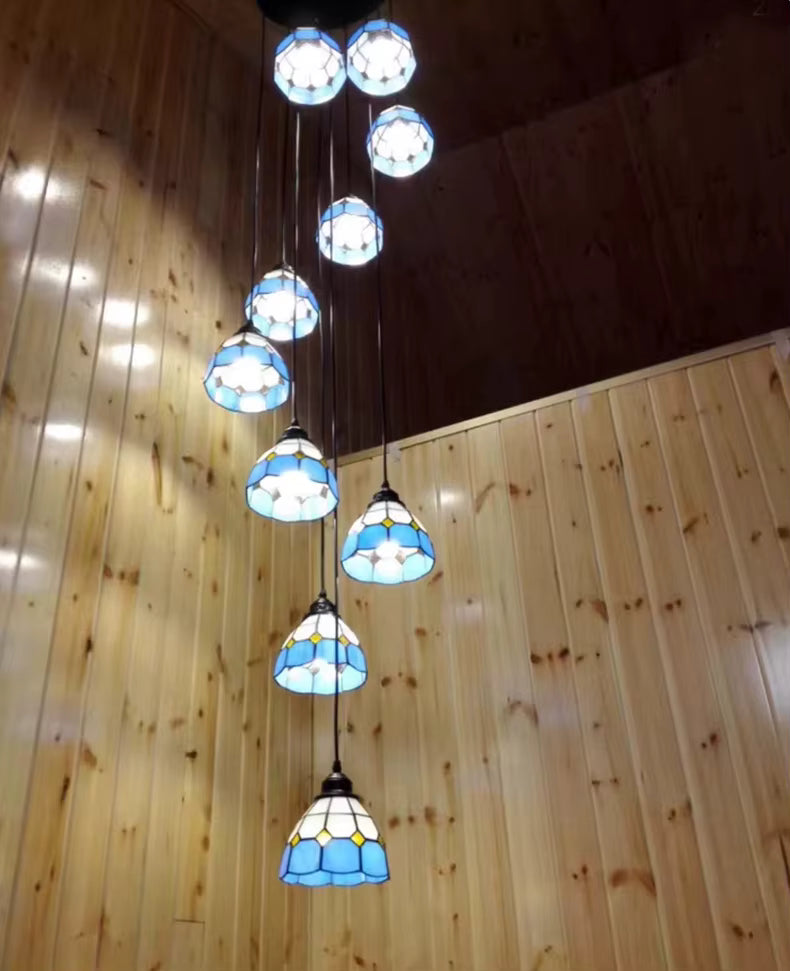 Grande suspension cascade Tiffany en vitrail bleu illuminant un intérieur chaleureux à haut plafond en bois