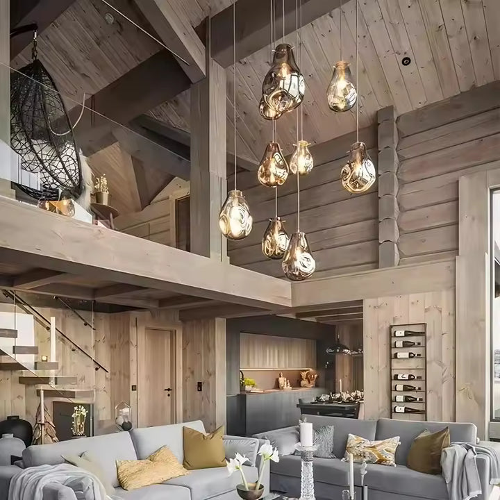 Huit suspensions en verre soufflé aux courbes organiques illuminent un salon de chalet contemporain avec mezzanine en bois.