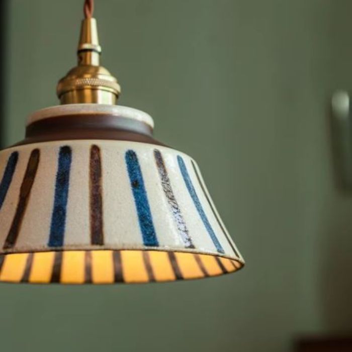 Suspension en céramique écrue à bandes bleues et brunes, style bohème et vintage, idéale pour une décoration intérieure chic et naturelle.