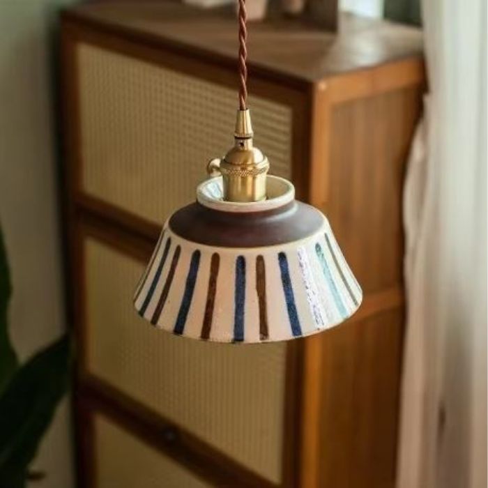 Suspension en céramique écrue avec bandes bleues et brunes, idéale pour une ambiance vintage et bohème, ajoutant une touche naturelle à votre décoration.