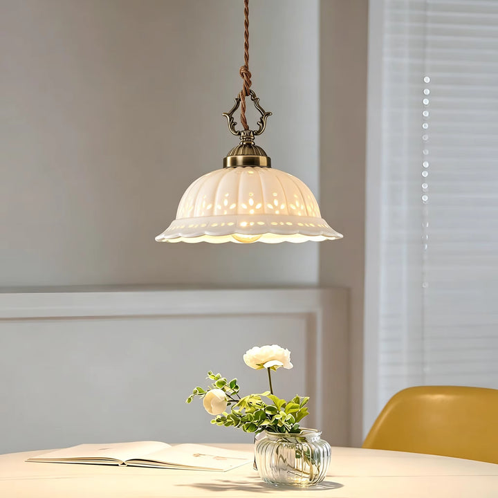 Au-dessus d’une table, suspension en céramique blanche ajourée et laiton vieilli au charme rétro élégant
