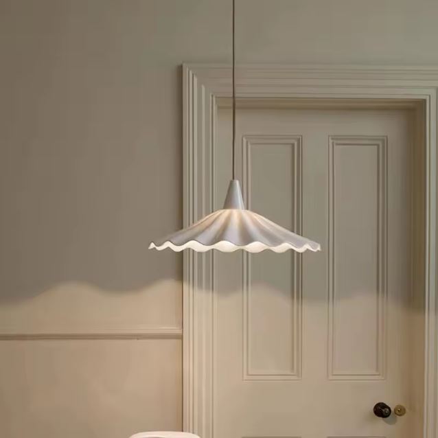 Suspension en céramique blanche ondulée effet jupe plissée, style campagne chic et raffiné dans un intérieur lumineux.