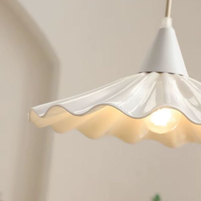 Suspension en céramique blanche ondulée effet jupe plissée, lumière chaude et style minimaliste apaisant.