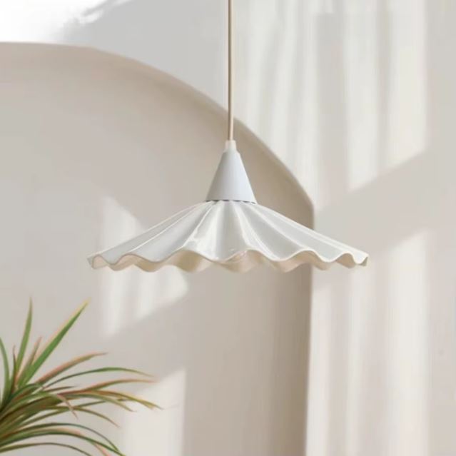 Suspension en céramique blanche ondulée effet jupe plissée, design organique et doux pour intérieur apaisant.