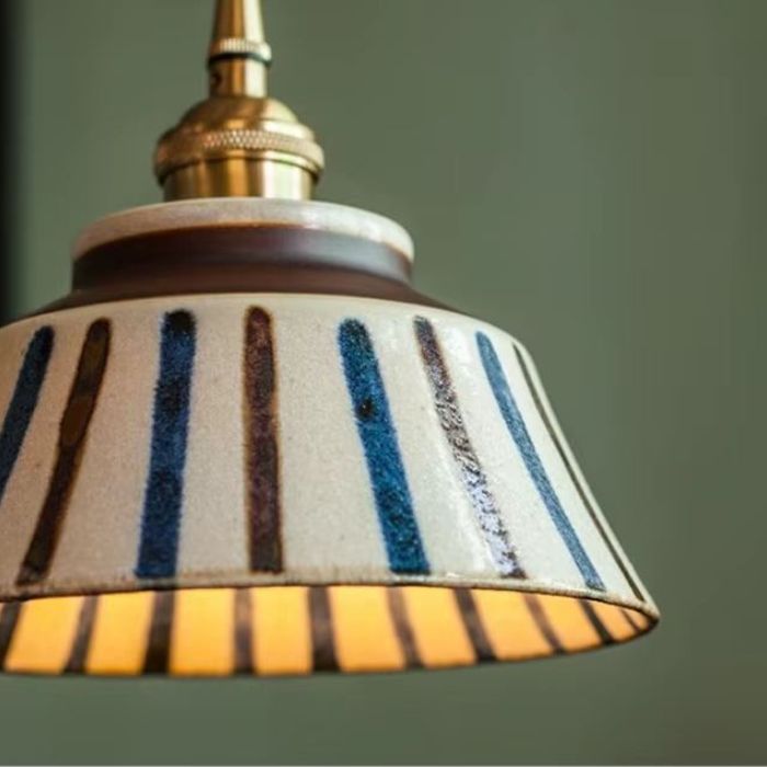 Détail de la suspension en céramique écrue avec motifs géométriques bleus et bruns, parfait pour une décoration vintage moderne et élégante.