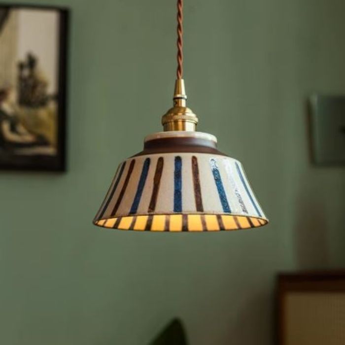 Suspension en céramique écrue avec bandes bleues et brunes, un éclairage vintage et élégant pour une ambiance chaleureuse et artistique dans votre intérieur.