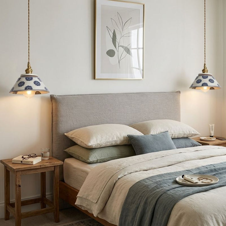Lampe suspendue en céramique à fleurs bleues installée comme luminaire de chevet dans une chambre à la décoration apaisante.