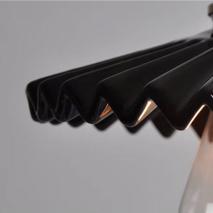 Suspension en céramique noire nervurée à collerette plissée, détail du bord plissé révélant un style art déco moderne et industriel raffiné.
