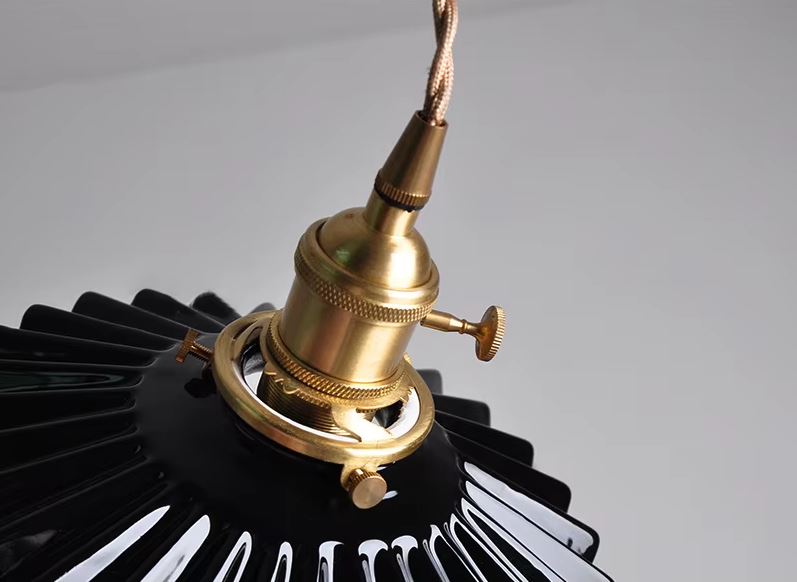 Suspension en céramique noire nervurée à collerette plissée, détail de la monture laiton évoquant un style industriel chic et contemporain élégant.