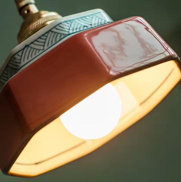 Gros plan sur la suspension en céramique rouge brique avec frise décorative, idéale pour une déco rétro ou artisanale authentique.