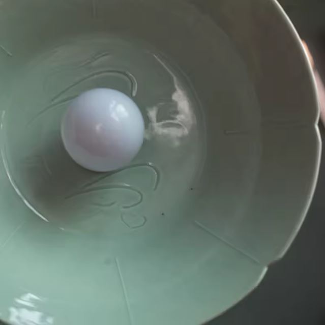 Suspension en céramique vert d’eau aux courbes ondées, vue intérieure révélant son style rétro épuré et son charme artisanal naturel.