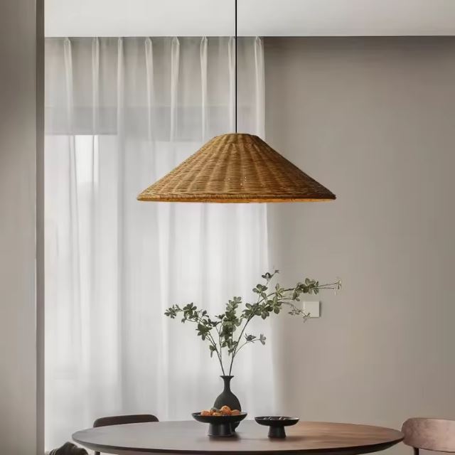 Suspension en forme de chapeau en rotin naturel suspendue au-dessus d'une table ronde dans un intérieur élégant et épuré.