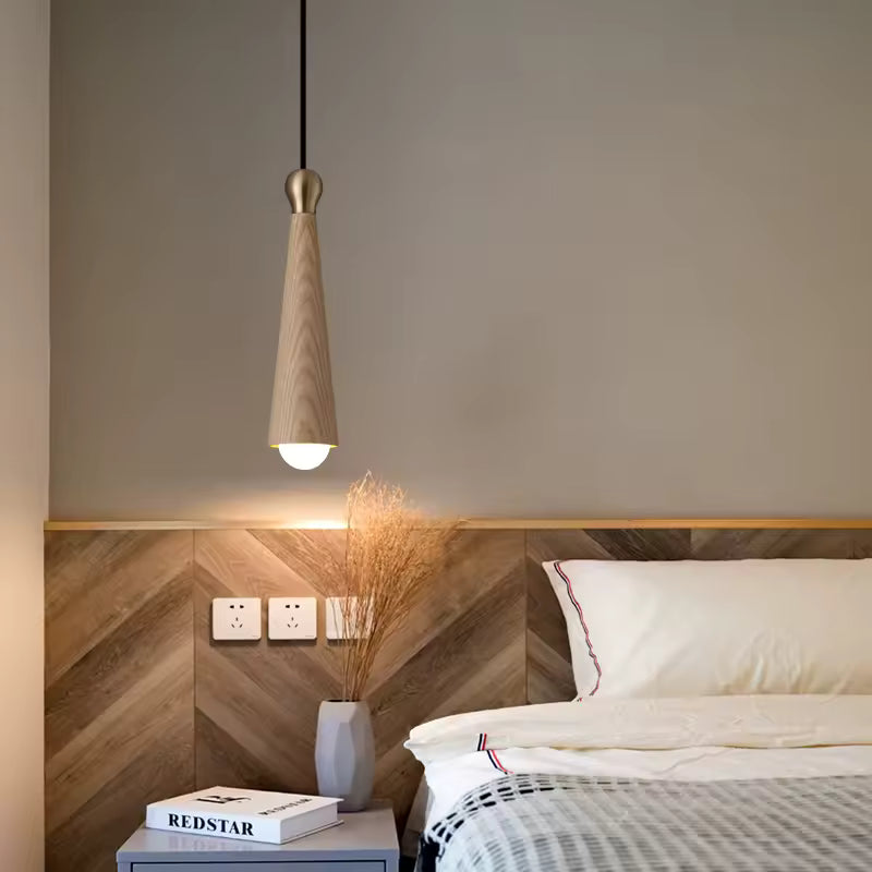 Dans une chambre chaleureuse, la suspension de chevet en bois de frêne clair et laiton affiche une forme conique épurée