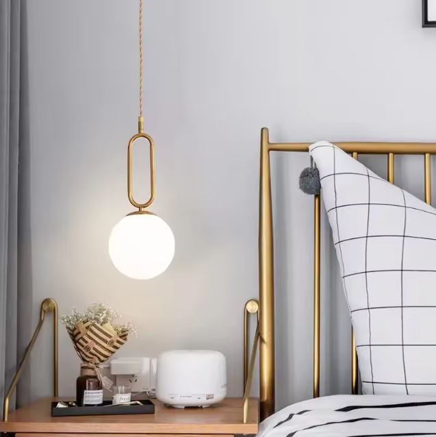 Suspension chevet en laiton avec globe blanc, luminaire contemporain au style italien pour une chambre élégante.