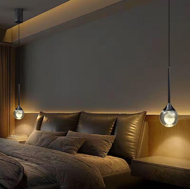 Suspension chevet en forme de goutte noire et transparente avec verre lumineux, éclairage chambre au style contemporain et chaleureux.