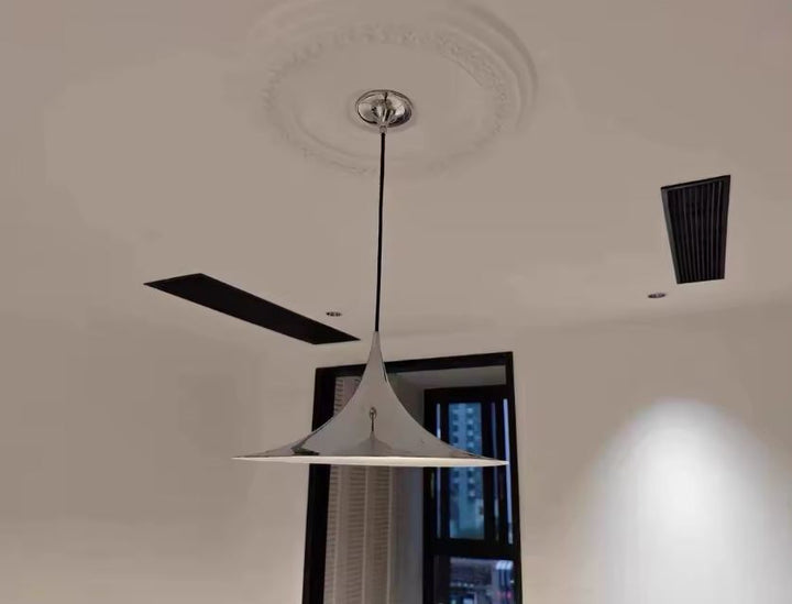 Suspension chrome effilée sous rosace de plafond, entre design italien, modernisme et allure rétro futuriste.