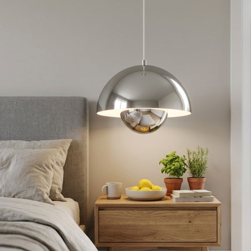 Suspension chromée à côté d'un lit, apportant une touche de design scandinave raffinée à la chambre.