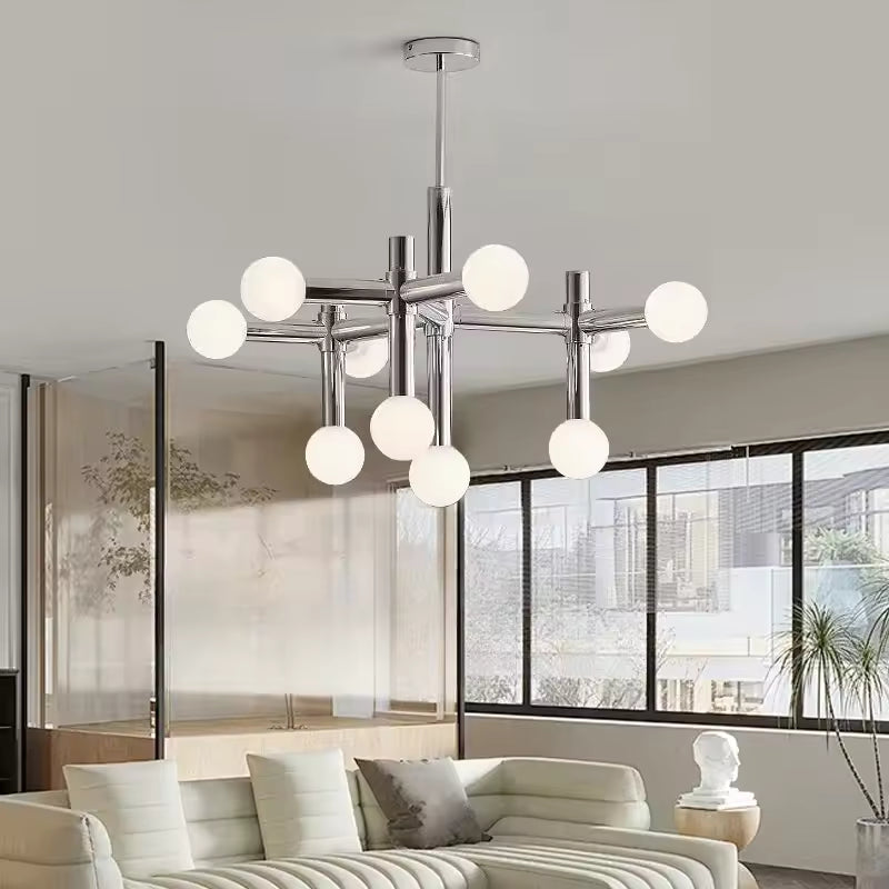 Suspension chromée à globes opalins dans un salon lumineux, avec une allure contemporaine et graphique