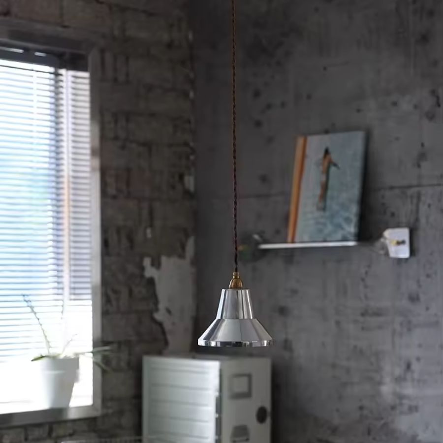 Dans un intérieur esprit loft, suspension chromée au design industriel vintage avec long câble torsadé