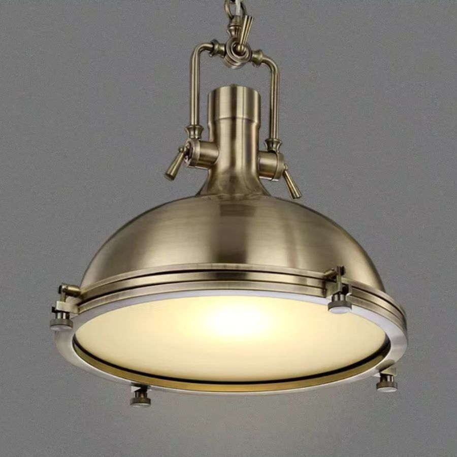Vue rapprochée d’une suspension cloche en laiton, au charme industriel ancien et à l’éclairage doux