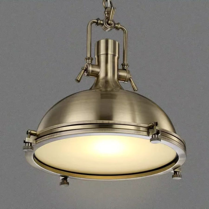 Vue rapprochée d’une suspension cloche en laiton, au charme industriel ancien et à l’éclairage doux