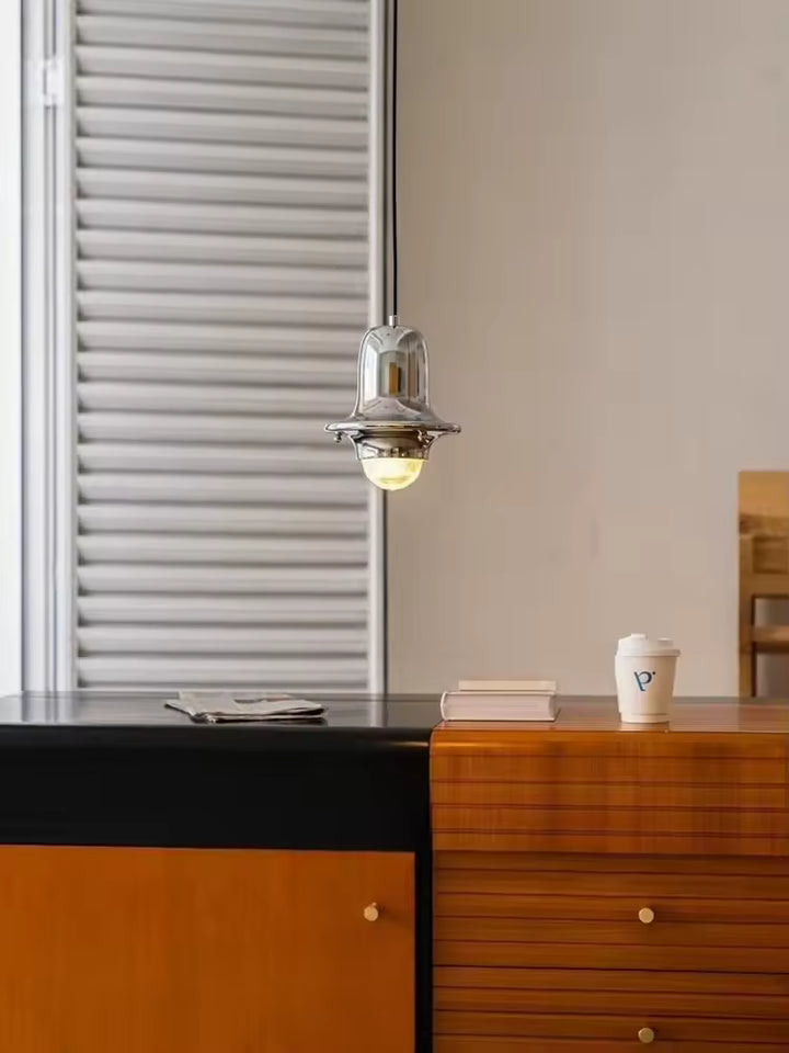Suspension cloche en métal chromé et verre strié, diffusant une lumière douce dans un intérieur au charme vintage