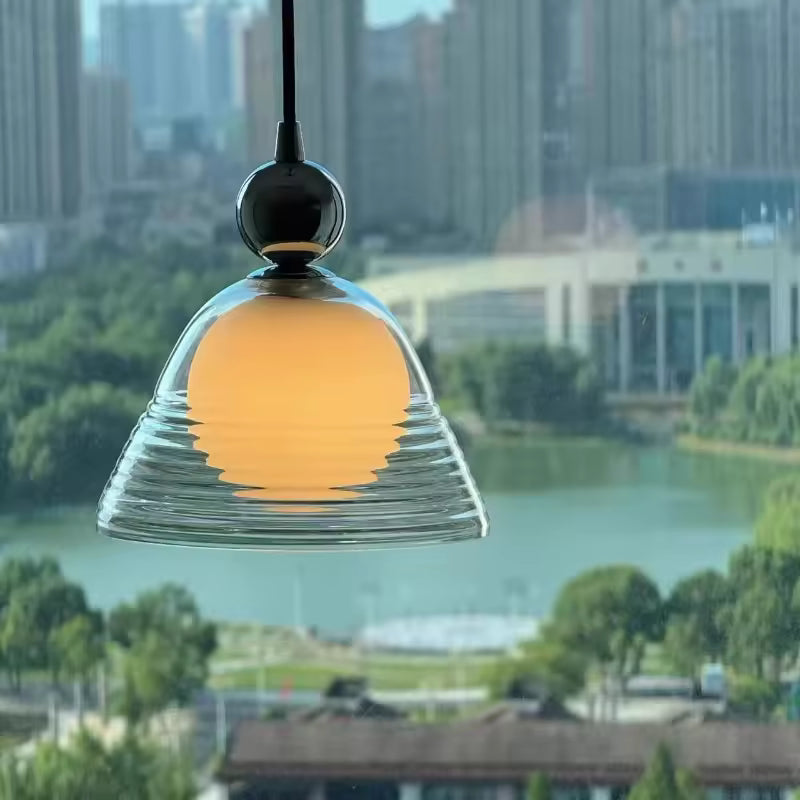 Luminaire en verre soufflé strié avec globe opalin, suspendu devant une fenêtre dans un esprit rétro contemporain