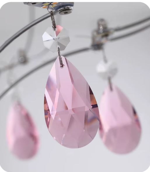Gros plan sur une pampille en cristal rose facetté d’une suspension cœur au style bijou et sophistiqué.
