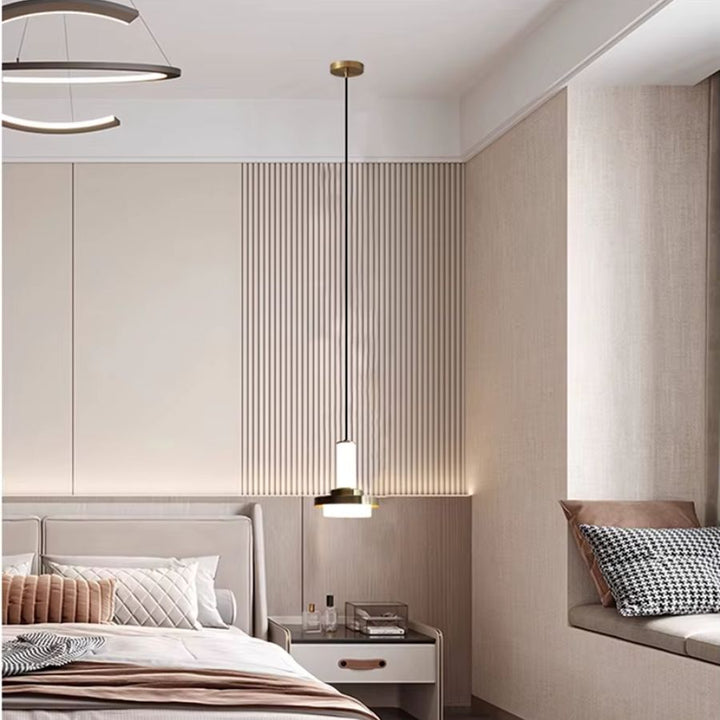 Installée en suspension de chevet, cette colonne à disque doré apporte une lumière douce dans une chambre contemporaine