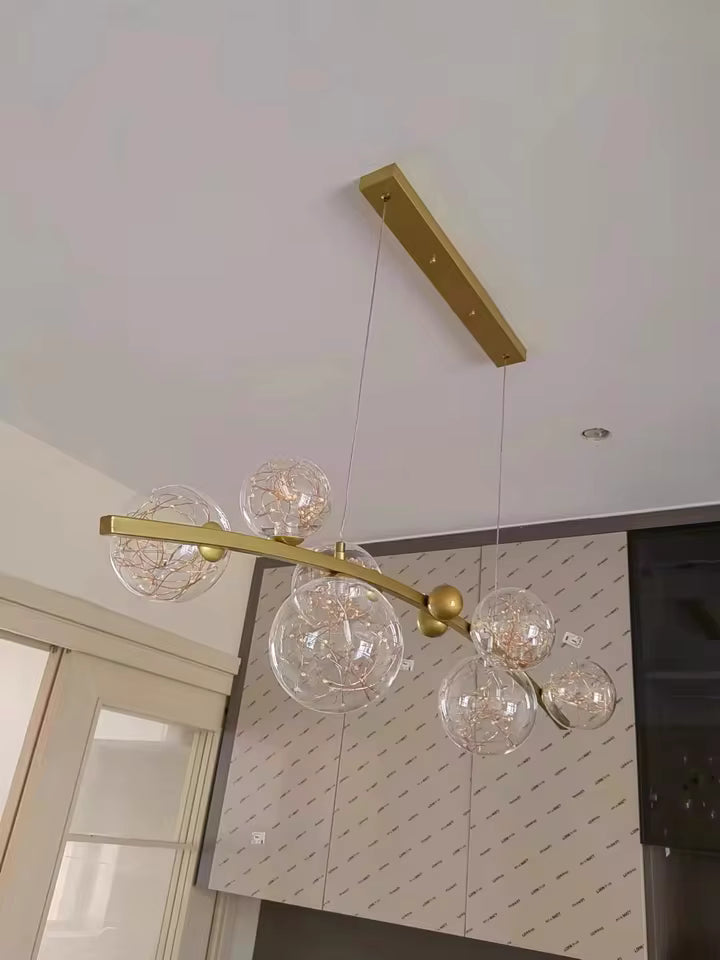 Suspension à globes en verre sur barre dorée, au design céleste et contemporain inspiré d'une constellation étoilée.