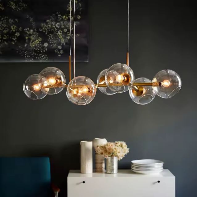 Suspension Constellation Linéaire à Globes en Verre transparent avec structure en laiton doré dans un salon contemporain et luxueux.