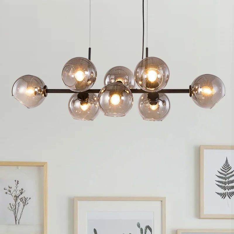 Suspension linéaire design structure en métal noir et globes en verre fumé mise en valeur sur un fond clair et épuré.