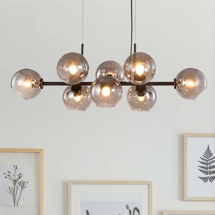 Suspension linéaire design structure en métal noir et globes en verre fumé mise en valeur sur un fond clair et épuré.